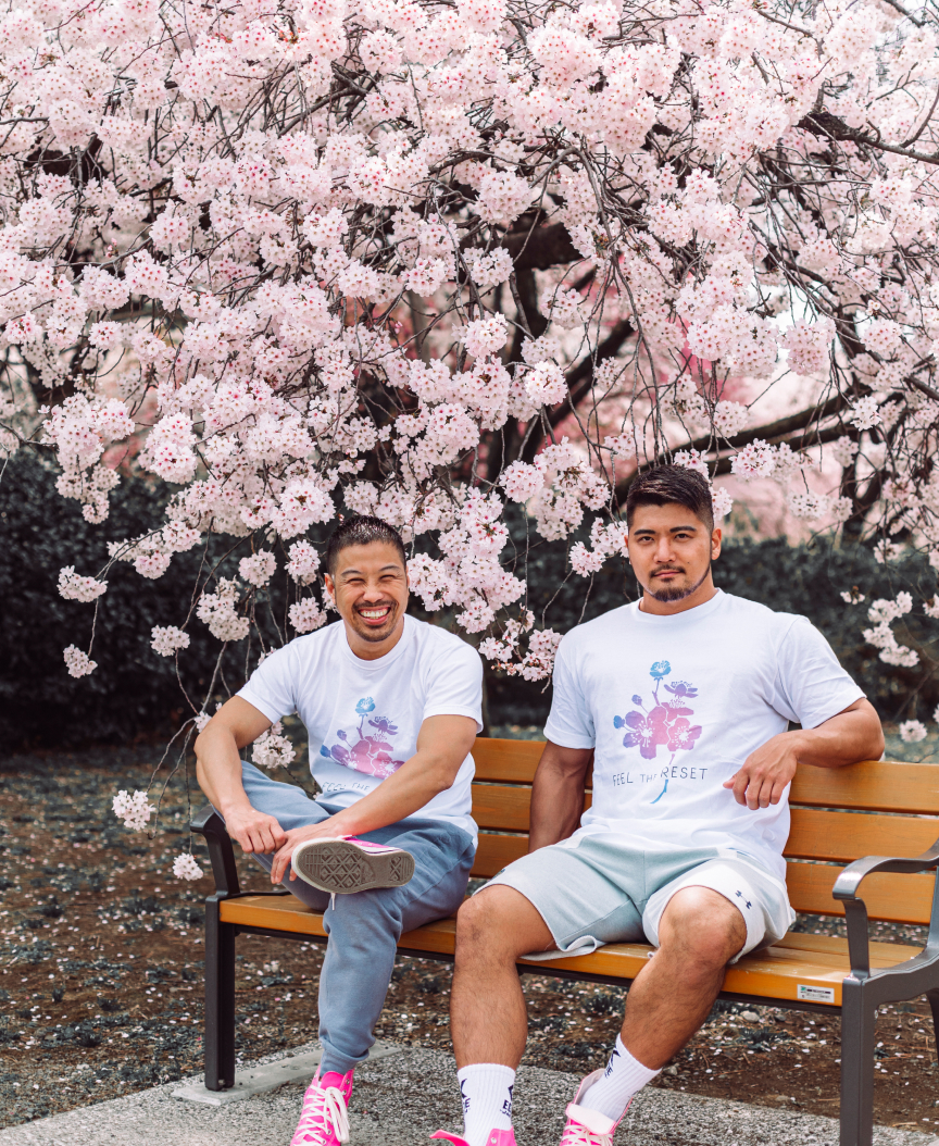 桜の下、鍼灸院ファイブエレメンツ7周年記念Tシャツの筋肉質男性GOGO SASUKEと鍼灸師